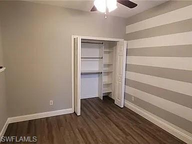 Unfurnished bedroom with dark wood-type flooring, ceiling fan, and a closet