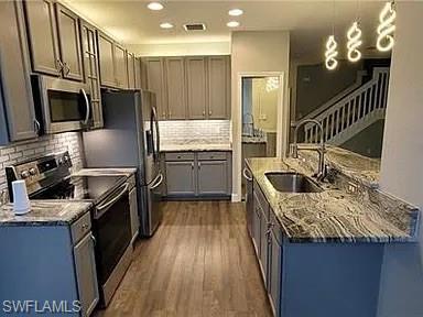 Kitchen featuring appliances with stainless steel finishes, dark stone countertops, dark wood finished floors, decorative backsplash, and recessed lighting