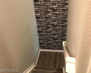Stairway featuring wood finished floors and a textured wall