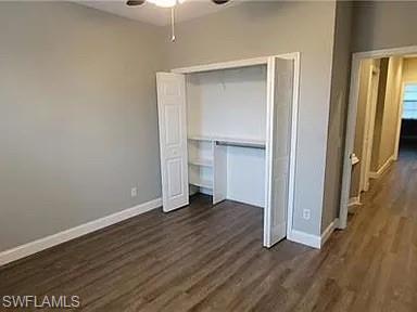 Unfurnished bedroom featuring dark wood-type flooring, a closet, and a ceiling fan