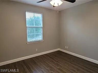 Empty room with baseboards and dark wood-type flooring