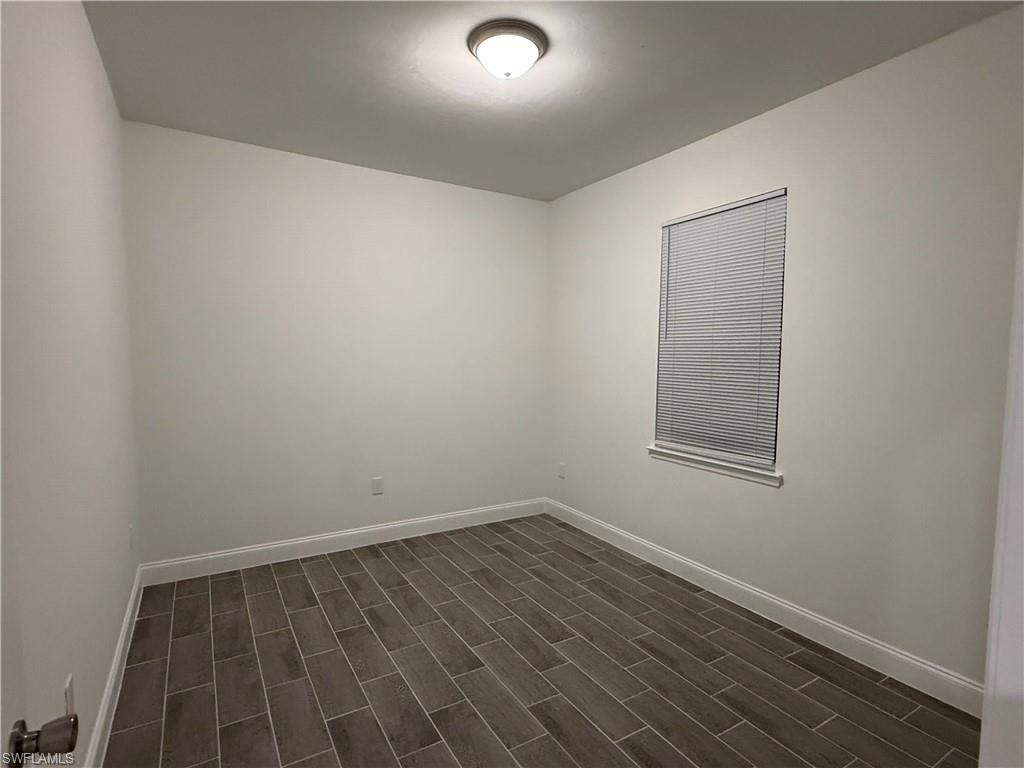 Unfurnished room featuring baseboards and dark wood-style floors
