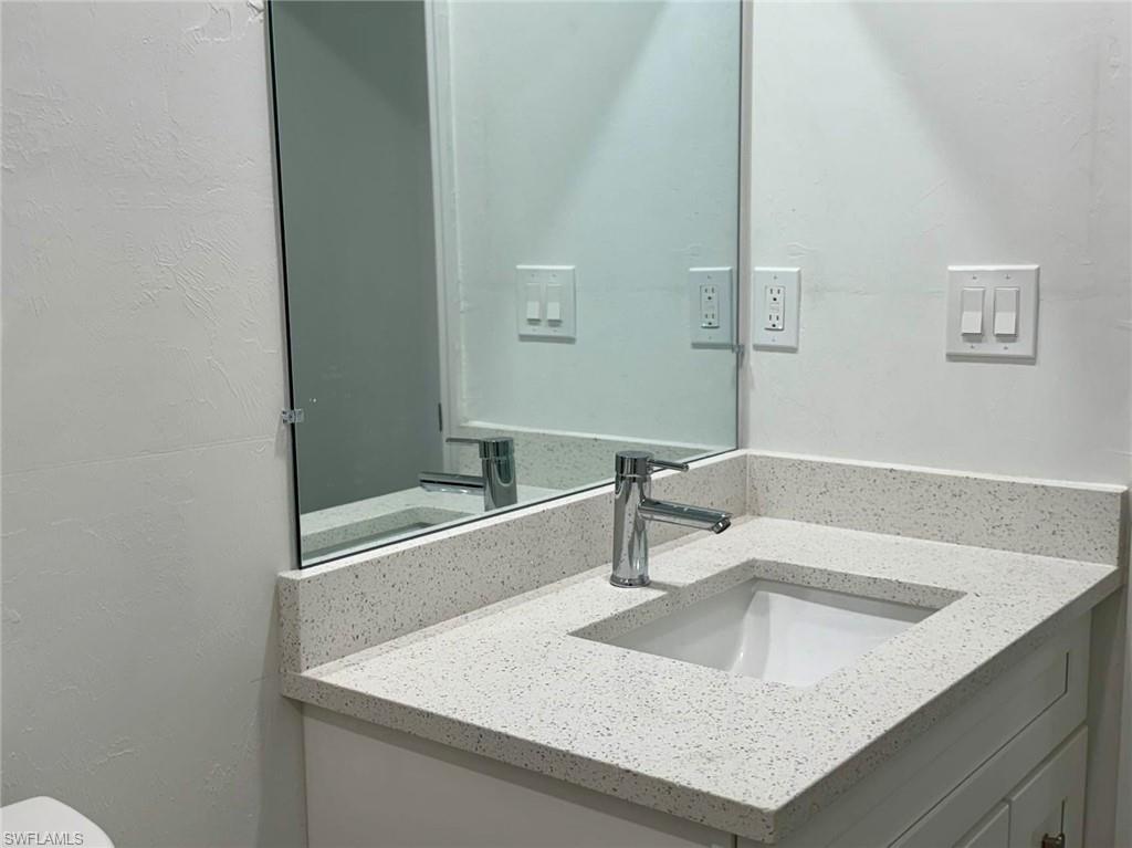 Half bathroom featuring vanity and a textured wall