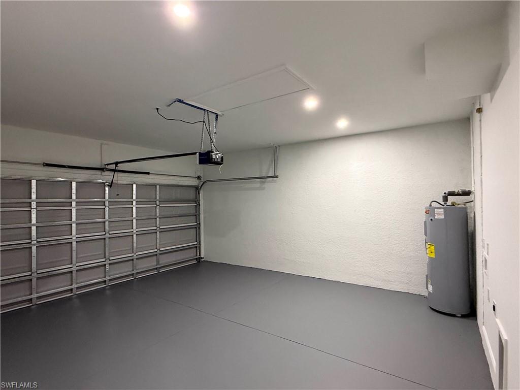 Garage featuring water heater, a textured wall, and a garage door opener