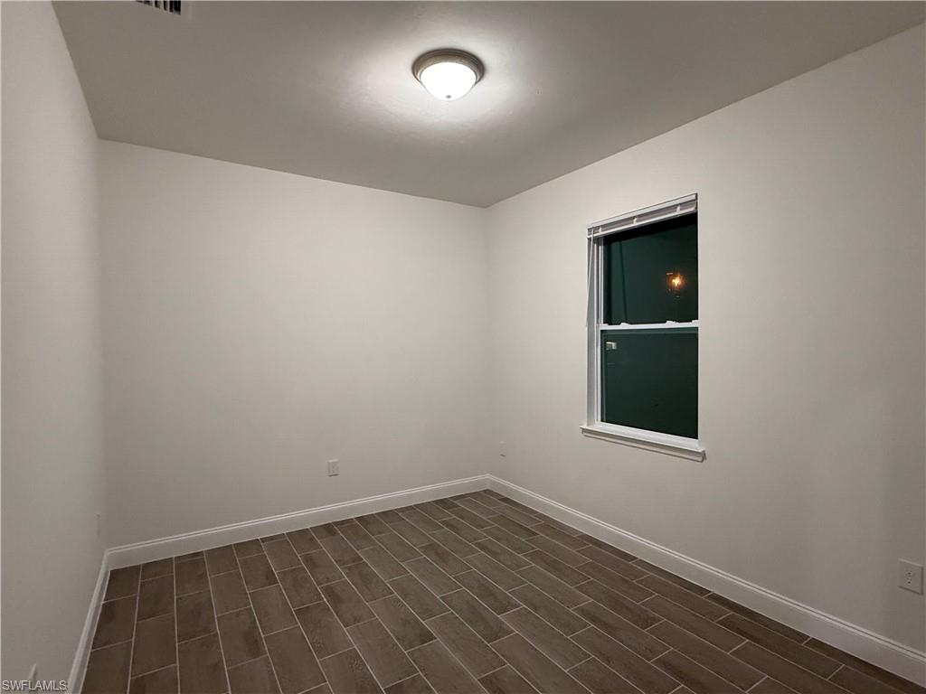 Empty room featuring baseboards and dark wood-style flooring