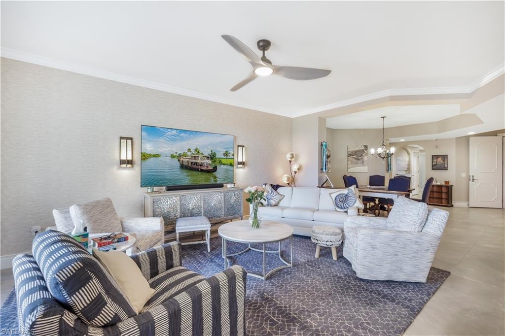 Living area featuring crown molding, ceiling fan, and a chandelier