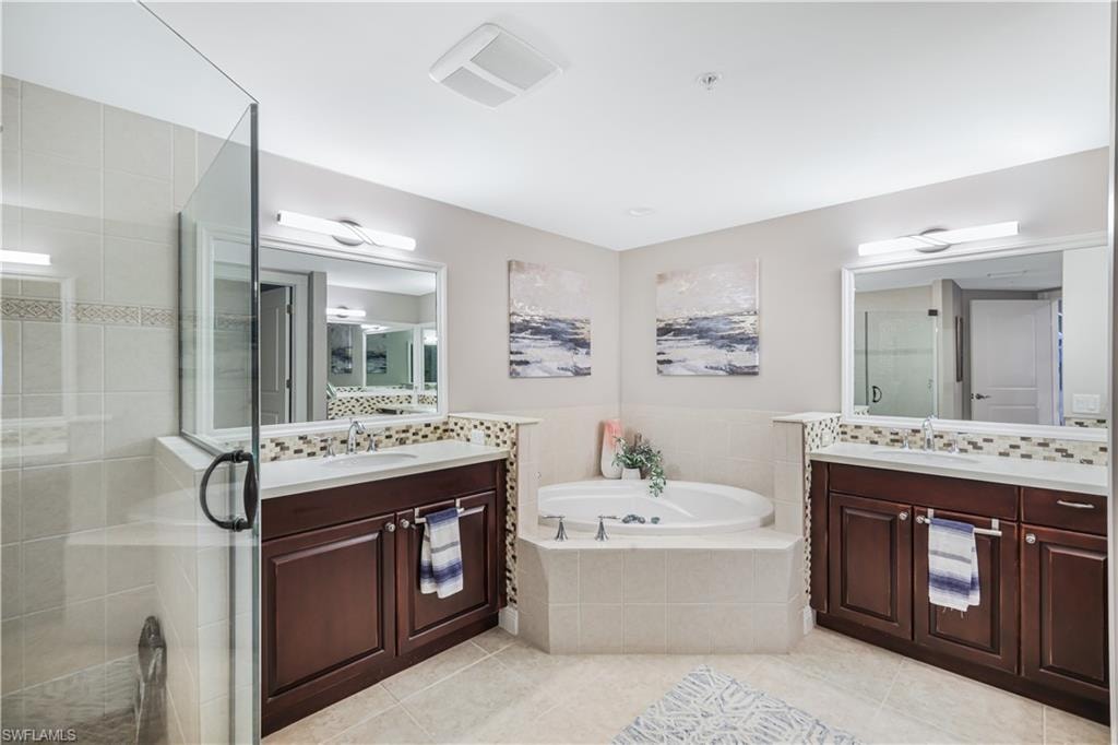 Bathroom with decorative backsplash, a jetted tub, two vanities, and a shower stall