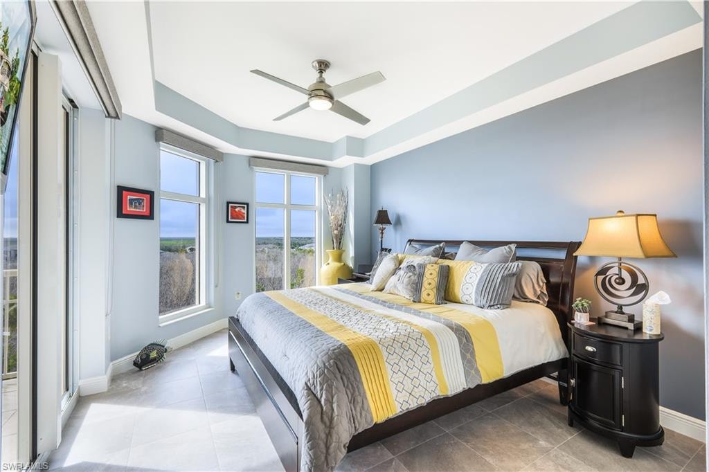 Bedroom with a ceiling fan, a raised ceiling, and tile patterned flooring