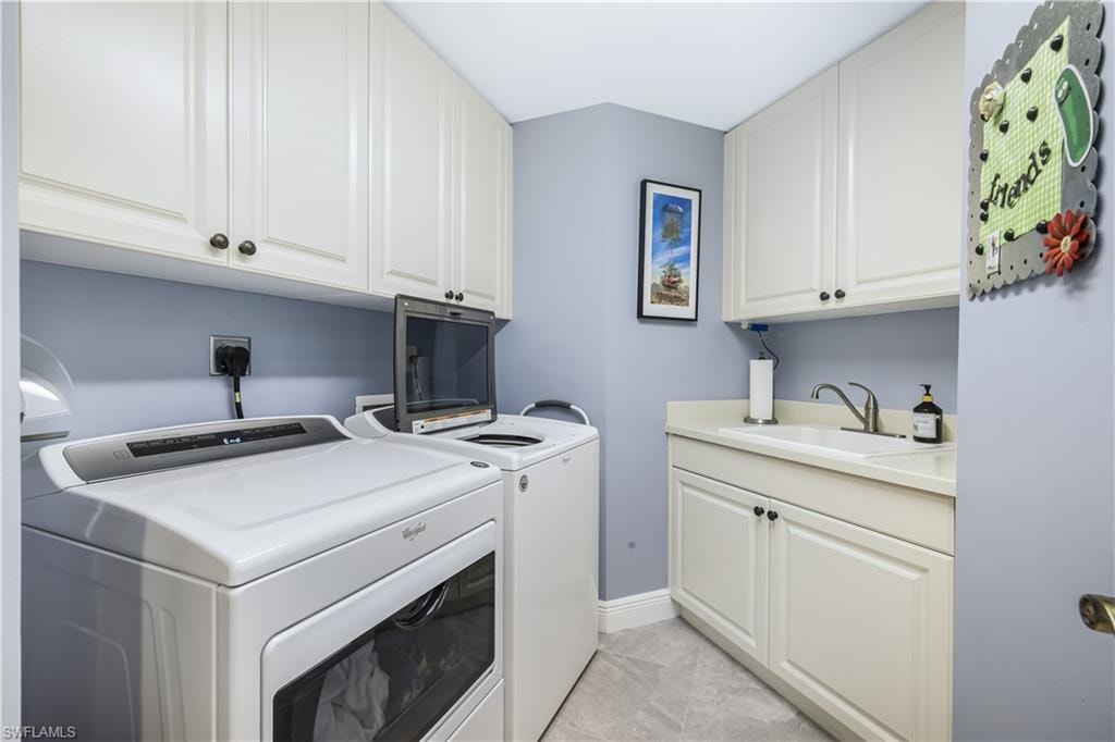 Washroom featuring cabinet space, independent washer and dryer, and light tile patterned flooring