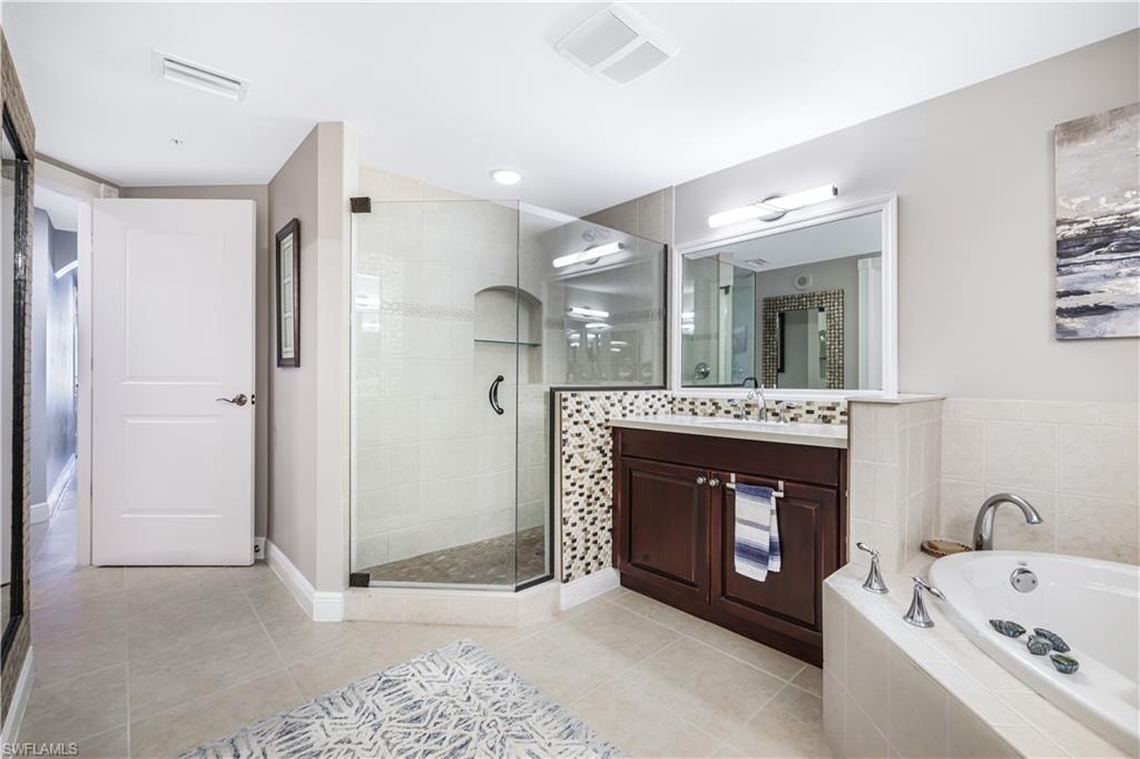 Bathroom with a garden tub, light tile patterned floors, vanity, and a stall shower