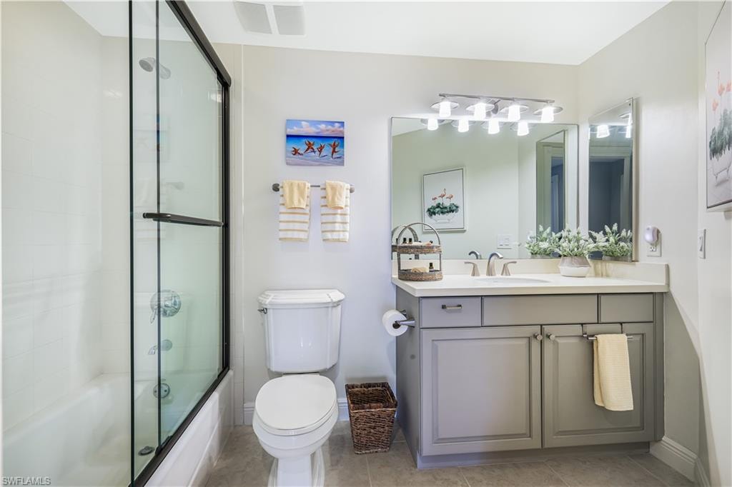 Full bathroom with vanity, light tile patterned flooring, and bath / shower combo with glass door
