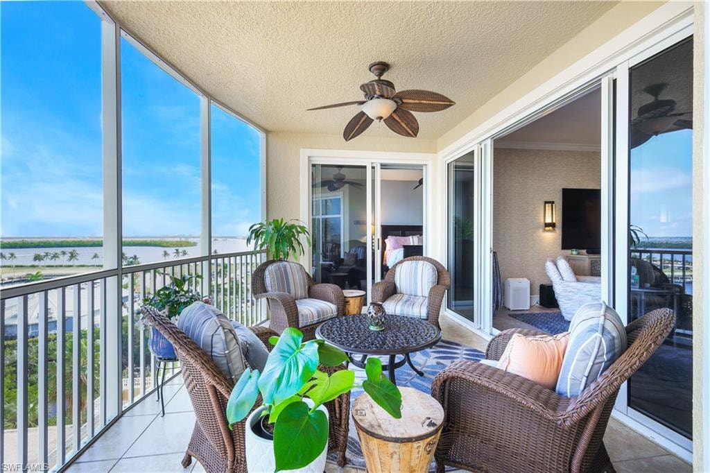 Sunroom / solarium with a water view, ceiling fan, and a balcony