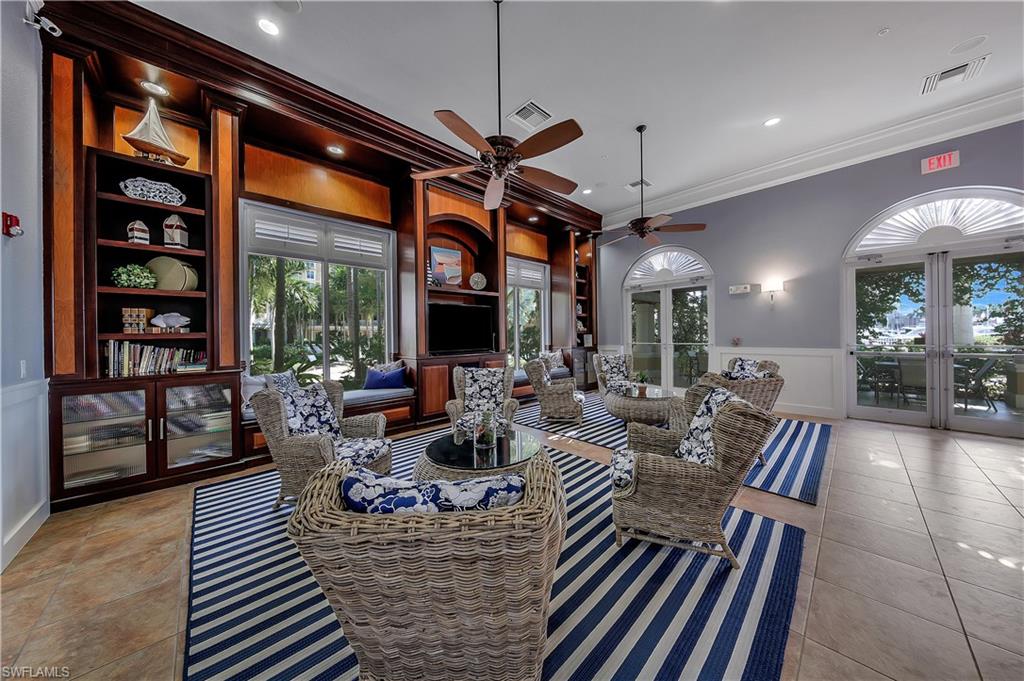 Living area featuring wainscoting, a ceiling fan, crown molding, light tile patterned flooring, and a decorative wall