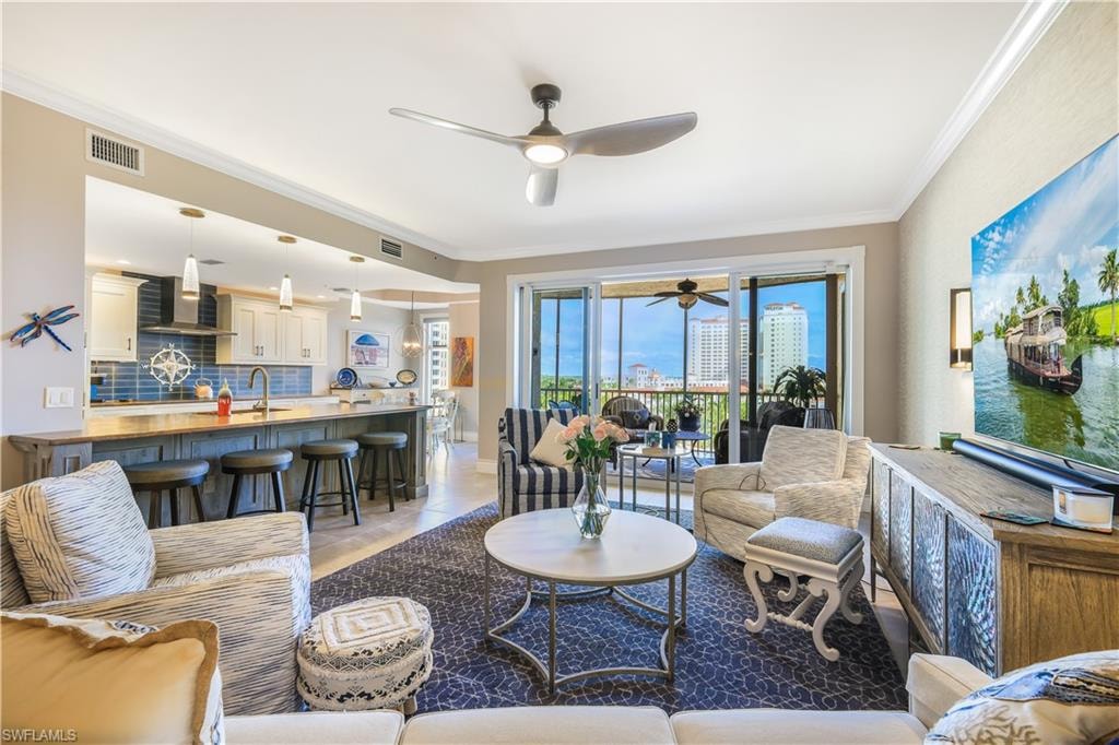 Living room with a ceiling fan, crown molding, and light tile patterned floors