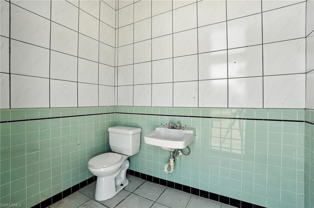 Half bath featuring tile patterned flooring and tile walls