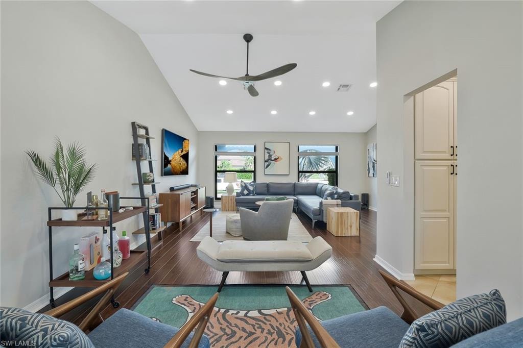 Living room featuring high vaulted ceiling, recessed lighting, dark wood-style floors, and a ceiling fan