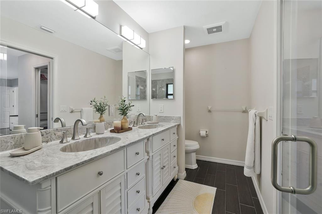 Bathroom with double vanity, wood tiled floors, and a shower stall
