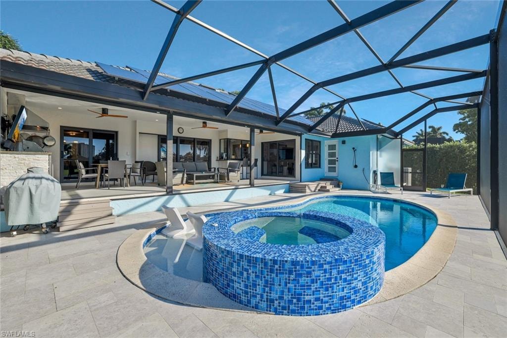 View of pool with ceiling fan, a patio area, a sunroom, a pool with connected hot tub, and glass enclosure
