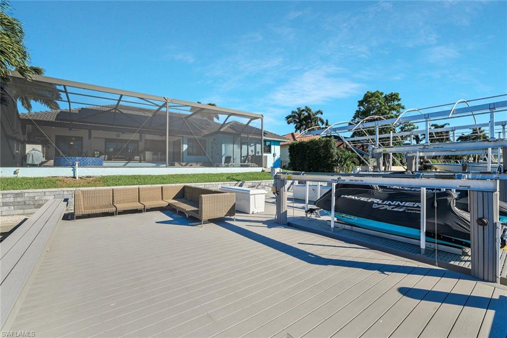 Deck with boat lift, glass enclosure, a dock, a sunroom, and an outdoor hangout area