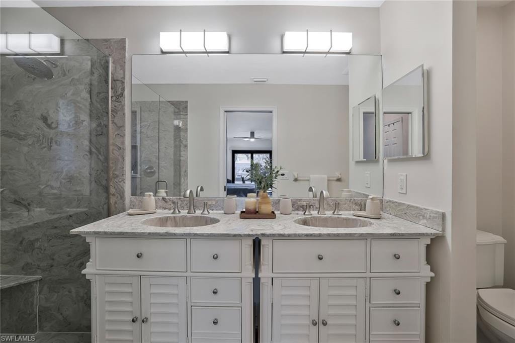 Bathroom with double vanity, a marble finish shower, and a ceiling fan