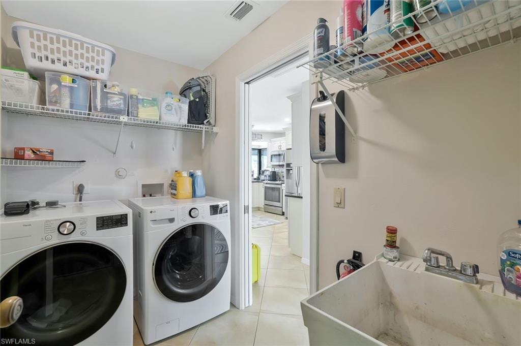 Laundry room with independent washer and dryer and light tile patterned floors