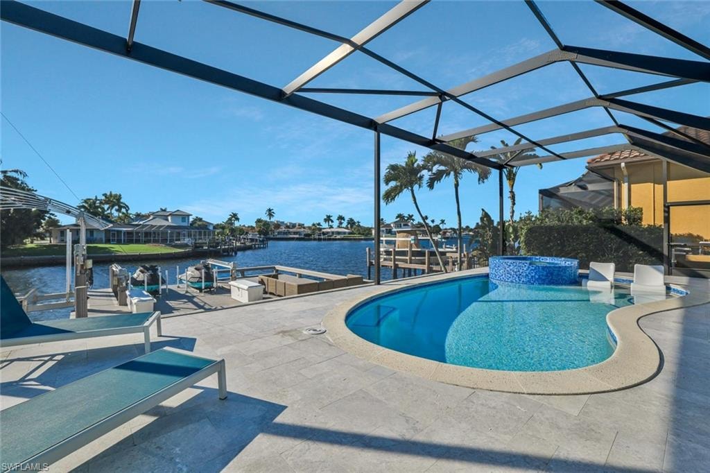 View of pool featuring a dock, a water view, a pool with connected hot tub, a patio, and glass enclosure