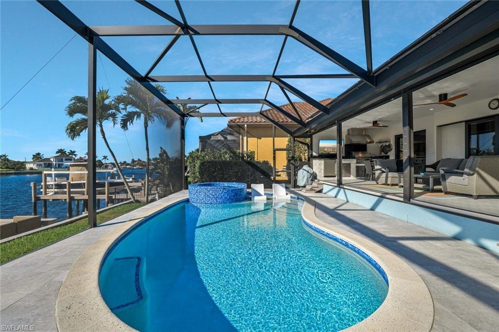 View of pool with a lanai, a sunroom, ceiling fan, a patio area, and an outdoor kitchen