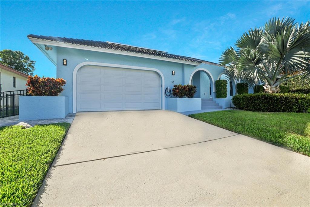 Mediterranean / spanish-style house featuring concrete driveway, stucco siding, an attached garage, and a front lawn