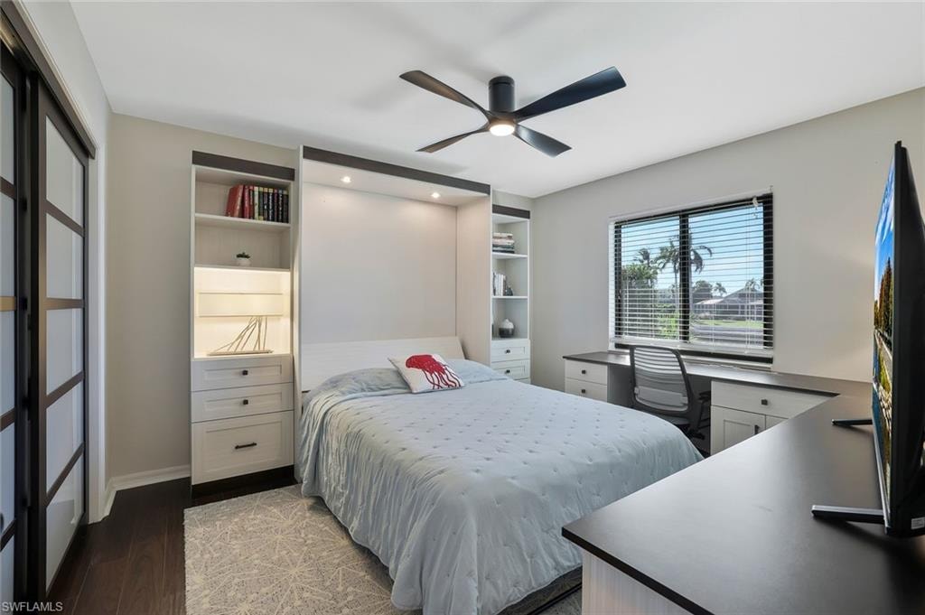 Bedroom featuring dark wood-style floors, a ceiling fan, and an office area