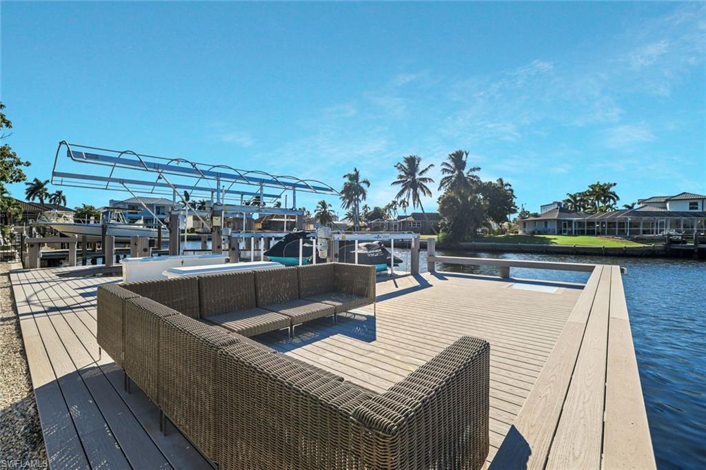 Dock area with a water view, boat lift, and a residential view