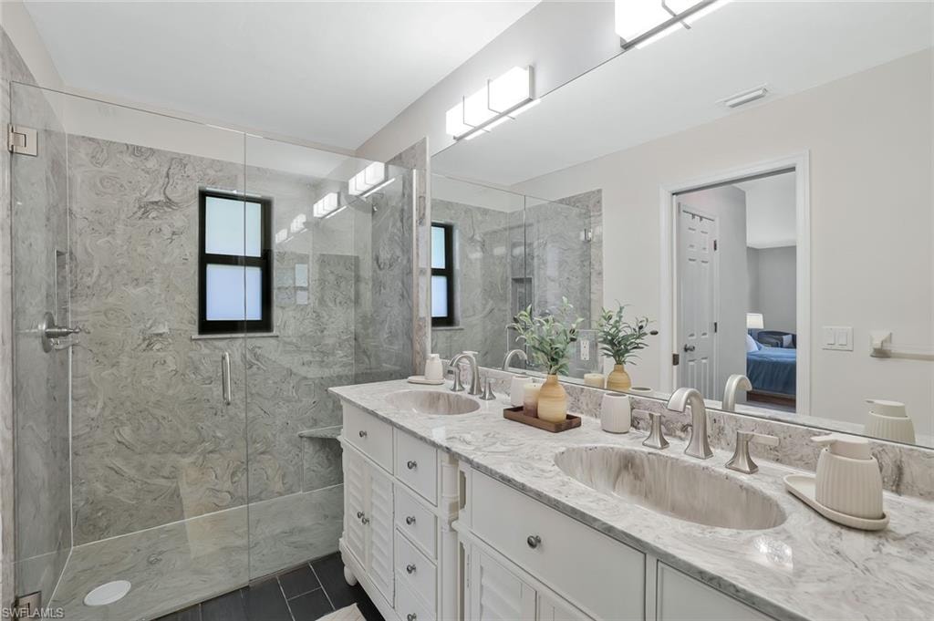Ensuite bathroom featuring double vanity and a marble finish shower