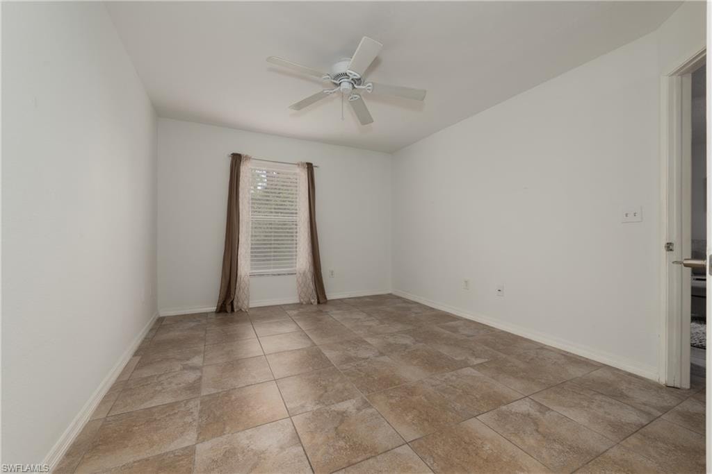 Unfurnished room featuring ceiling fan and baseboards
