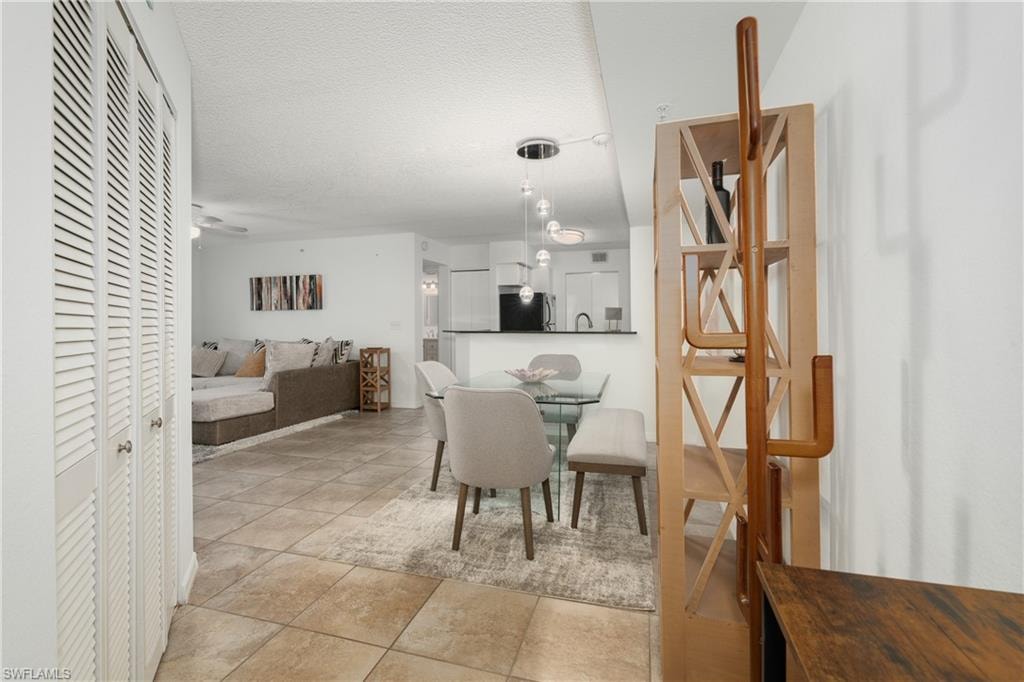 Dining space with light tile patterned flooring, a textured ceiling, and ceiling fan