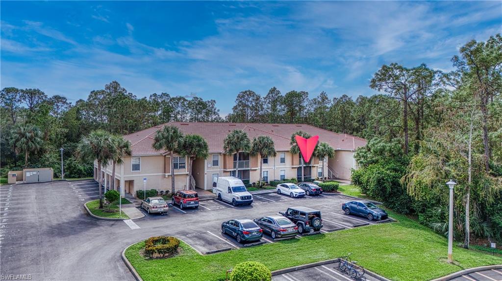 View of front of property featuring uncovered parking, view of wooded area, and a front lawn