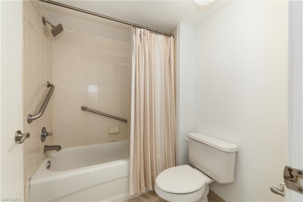 Bathroom with shower / bathtub combination with curtain and toilet