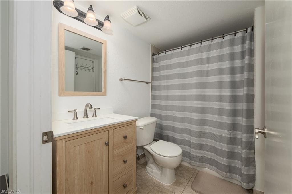 Full bathroom with curtained shower, vanity, and light tile patterned flooring