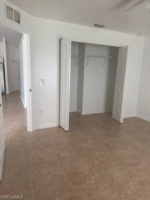 Unfurnished bedroom featuring a closet, a ceiling fan, and light tile patterned floors