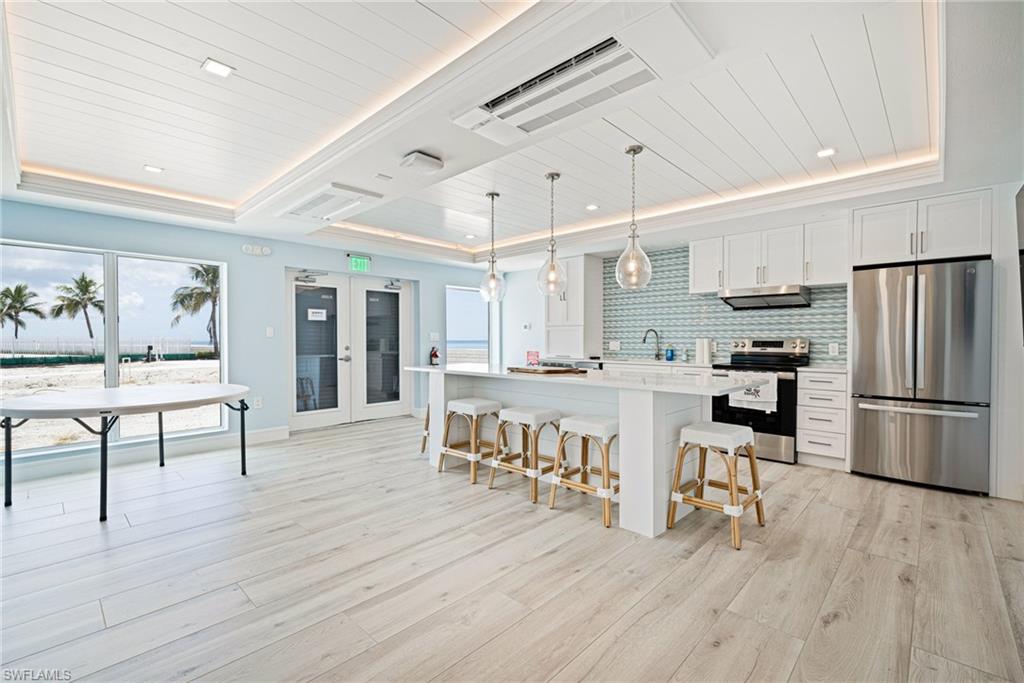 Kitchen featuring stainless steel appliances, wooden ceiling, a breakfast bar area, white cabinetry, and plenty of natural light