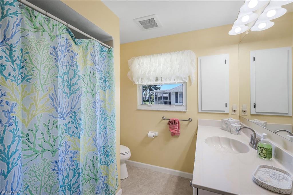 Full bath featuring vanity, a shower with shower curtain, light tile patterned floors, and a chandelier