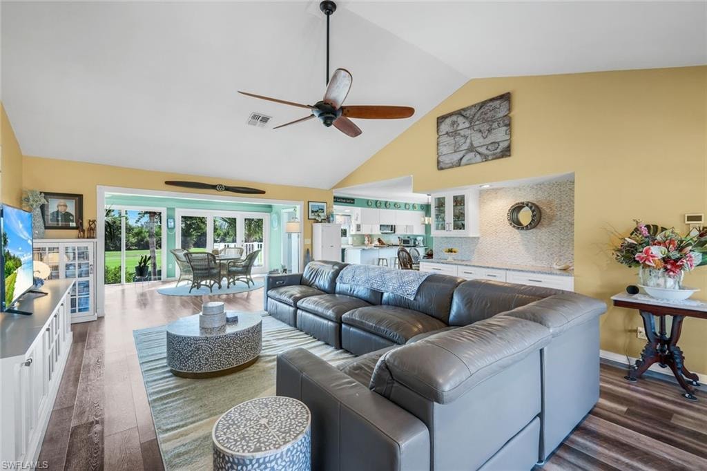 Living area featuring high vaulted ceiling, ceiling fan, and dark wood-style floors