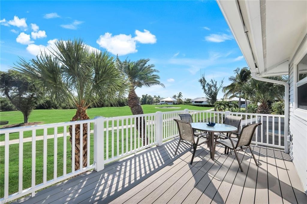 Wooden terrace featuring outdoor dining area and a lawn