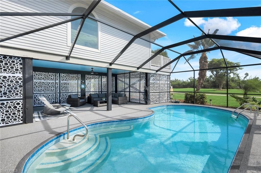 Swimming pool featuring a sunroom, a patio area, glass enclosure, outdoor lounge area, and ceiling fan