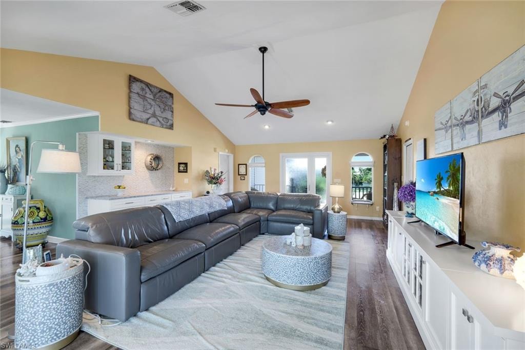 Living area featuring high vaulted ceiling, dark wood-style floors, and ceiling fan