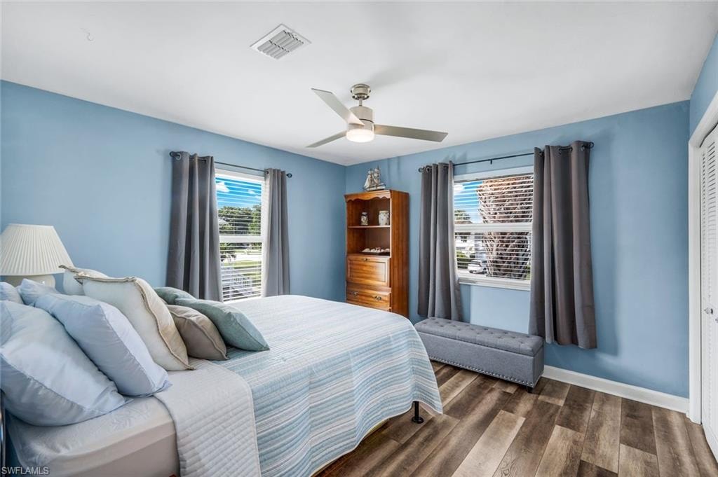 Bedroom featuring multiple windows, wood finished floors, a ceiling fan, and a closet