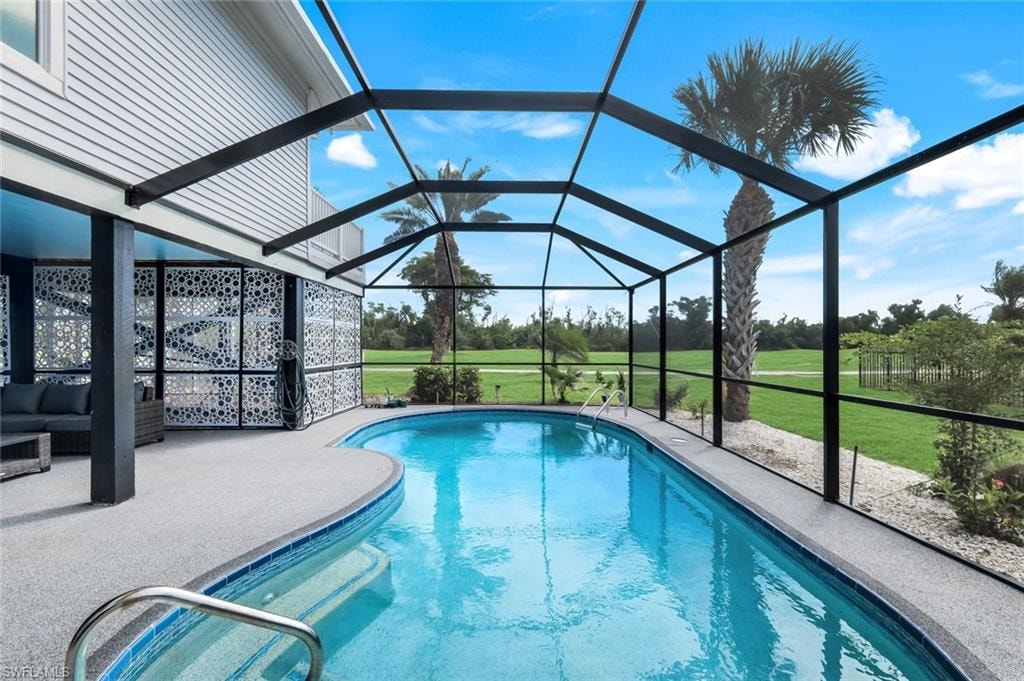 Swimming pool with a lawn, a sunroom, a lanai, and a patio area