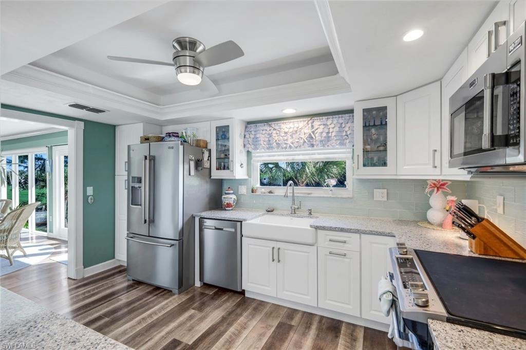 Kitchen featuring a raised ceiling, white cabinetry, light stone countertops, and recessed lighting