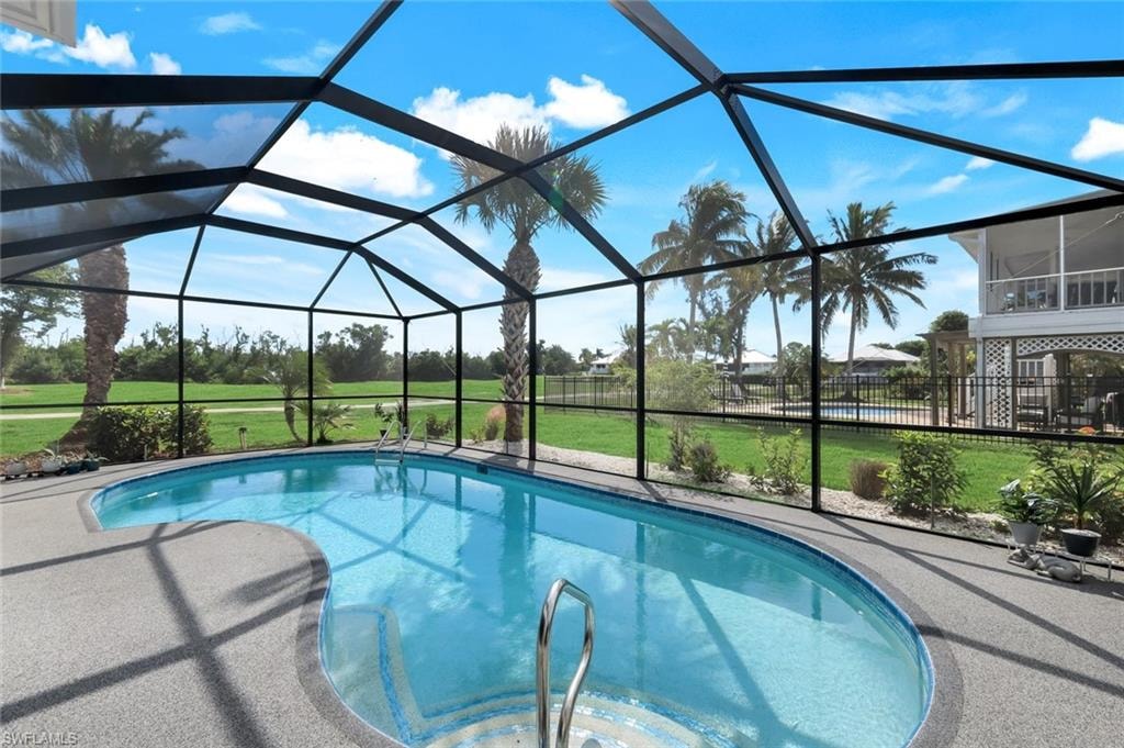 Outdoor pool featuring a sunroom and glass enclosure
