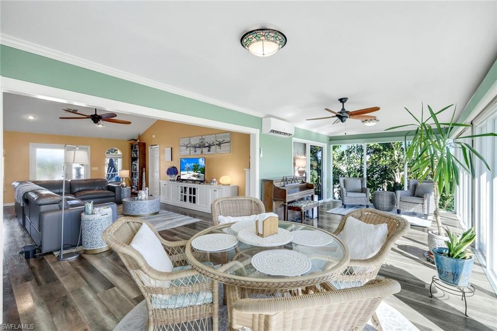 Dining space with a ceiling fan, plenty of natural light, wood finished floors, and lofted ceiling