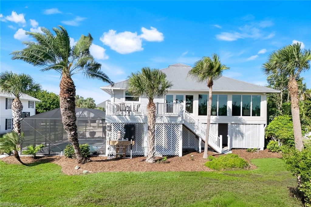 Back of house featuring a sunroom, a deck, stairway, glass enclosure, and a lawn