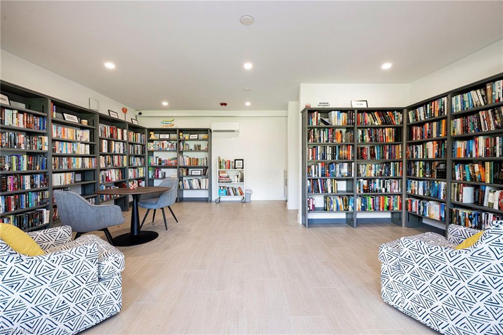 Living area with wall of books, recessed lighting, and a wall mounted AC